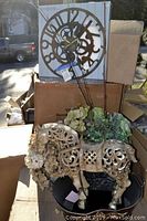 Horse statuette with floral faux flowers placed in basket, rustic gear clock in box behind