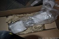 Two Paparazzi Topaz leaf wall sconces wrapped in bubble wrap inside an open shipping box with paper cushioning.