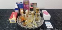 Front angled view of 22 assorted perfume bottles with glass tray on black surface