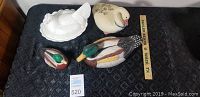 Four bird decor pieces with mallard ducks, white duck, and milk glass hen on nest on dark fabric background.