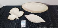 Three porcelain pieces including a leaf dish, an oval bowl, and a narrow leaf plate, placed on black fabric background.