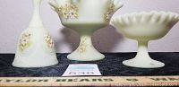 Close-up view of three Fenton glass items showing detailed hand-painted floral decorations on bell and stemmed dishes.
