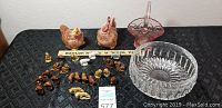 Full view of glass and ceramic items including two ceramic hen shakers, pink glass basket, clear glass bowl, and various small red rose tea and animal figurines.