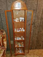 Full view of the entire cabinet showing height and openness with figurines inside.