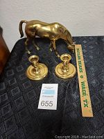 Brass horse figurine with a polished golden finish and two brass candle holders on a dark patterned surface, showing scale alongside a wooden Baylor Bears Waco TX ruler.