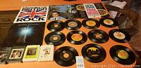 Photo showing vinyl albums History of British Rock, Barbara Streisand Christmas Album and 25 Polka Greats, along with several 45 RPM singles arranged below them, plus 8-track tapes on the side.