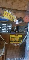 View of pegboard with various garage tools including yellow drill bit set, hardware organizers, buffing wheel, and other tools
