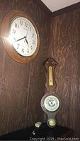 Photo showing the Seiko wall clock mounted on wood-paneled wall and wood barometer hung below, both vintage style.