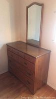 Full view of Ethan Allen dresser with attached mirror, medium brown wood finish, showing surface wear and dings