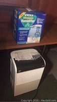 Vicks Ultrasonic Humidifier in box on shelf with Kenmore Dehumidifier below it