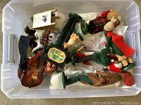Photo of plastic storage tote filled with Byers Choice festive figurines including carolers, some laying down showing details such as musical instruments and traditional clothing.
