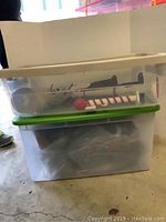 Two large plastic storage totes stacked with Christmas decorations inside