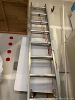 Full length view of the Werner aluminum extension ladder leaning against the wall shows the full ladder structure and pulley rope system.