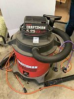 Overall front view of Craftsman 16 gallon wet/dry shop vacuum with attached hose and extension cord at base.
