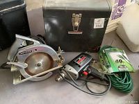 Craftsman circular hand saw with metal case, Craftsman electric drill, and green extension cord coiled on floor