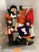 Photo showing multiple Byers Choice Halloween dolls with detailed costumes and hats including witches and characters, arranged in a plastic container.