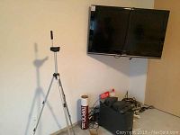 Wall-mounted Toshiba flat-screen TV, tripod, Bose speaker system control unit and cables on floor