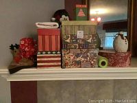 Stack of assorted Christmas-themed gift boxes in various sizes and styles placed on a mantle.