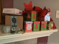 Photo showing Christmas themed storage boxes, large red bows, round tin, glass candle holders on mantle.
