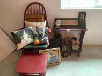 Image showing red rocking chair with green cushions, matching footstool, cat pillows, framed cat art and side table with family clock, sign and wooden house figurines.