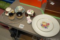 Teacups, saucers, pottery items, salt and pepper shakers arranged on table.