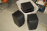 Technics Mini Changer System main unit inside white storage bin with several cables visible, two black Technics speakers placed in front