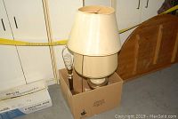 Three lamps grouped in a cardboard box, two with lampshades, one bare bulb, clearly worn and dusty