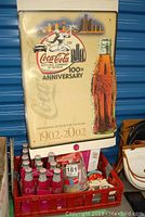 2002 Coca Cola Detroit 100th anniversary poster, showing the poster with Coca Cola bottle image and logos, creases visible at bottom
