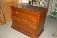 Front angled view showing three drawers with wooden knobs, scratches and nicks on surface, solid wood construction.