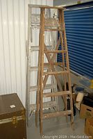 Wood and metal ladders leaning against a wall inside a storage unit showing condition and size.