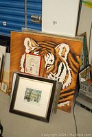 Large 36x36 tiger painting visible along with smaller framed print and watercolor behind it in corner of room