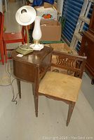 Full view of vintage wooden telephone table with upholstered seat and two lamps on top, showing overall condition and size.