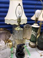 Photo showing two 25-inch crystal and brass lamps with large white scalloped fabric shades, a 12-inch glass base lamp with scalloped fabric shade, and a 9-inch dark green ceramic lamp with floral motif and beige fabric shade.
