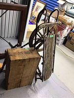 Antique wooden spinning wheel, weathered wooden sled, and Drambuie crate grouped together in storage.