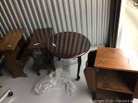 Four small wooden tables in storage with visible green lot tags.