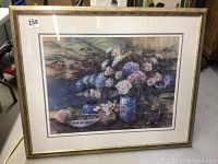 Framed floral print artwork showing floral vases with flowers and ornamental screen style landscape background.