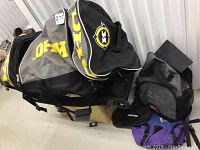 Large black and yellow Koho hockey bag, kids hockey gear including helmet, and a Kooga backpack and smaller bags in the background.