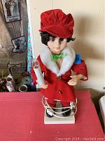 Front view of the vintage figurine showing red velvet coat, hat, and the lighted candle held in right hand.