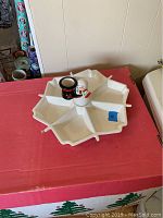 Full view of the white plastic sectioned serving dish with six compartments and a central holder with a snowman figure and black holder.