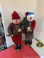 Photo showing both Mr and Mrs Snowman standing figurines side by side against a white wall background.