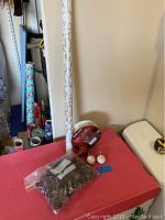 Snowman salt and pepper shakers, bag of scented pine cones, rolls of wrapping paper on red surface.