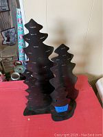 Front view of all four black metal Christmas tree tea light holders together, showing size variations and tea light slots.