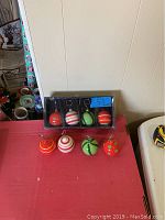 Box with 8 ceramic Christmas ball place card holders in various red, white, and green patterns plus four holders out in front