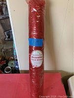 Full view of the red mesh ribbon roll wrapped in plastic with blue tape labeled '59'.