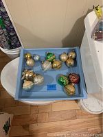 Blue tray holding 12 assorted Christmas ball ornaments in multiple colors and patterns