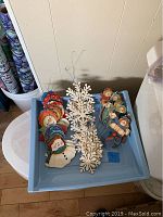 Top view of tray holding 29 assorted Christmas ornaments including snowflakes and snowmen grouped separately.