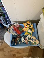 Assortment of 21 wooden Christmas ornaments in a plastic bin, showing various shapes and hand-painted designs including snowmen, stars, and hearts.