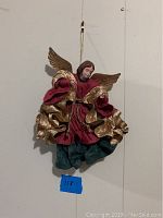 Front view of the angel figurine showing wings, garment details, and hanging string.