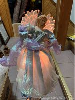 Front view of angel tree topper lit with orange and red glowing wings and iridescent gown.