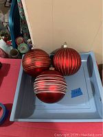 Photo showing all three large Christmas balls in a blue tray with red bases and gold or silver glitter stripes